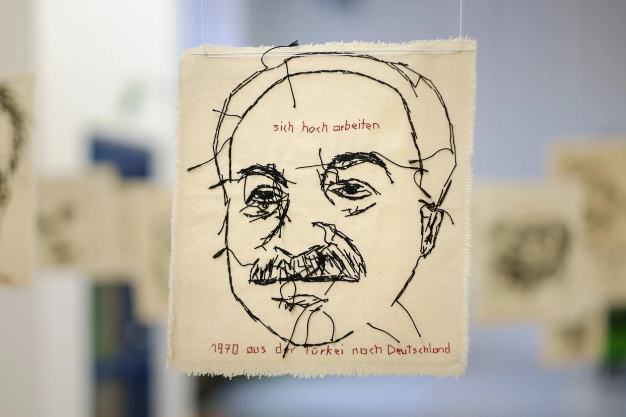 Skizzenhafte Zeichnung eines Mannes mit Schnurrbart, gezeichnet auf einem beigen Hintergrund. Die Skizze enth&auml;lt handschriftliche Notizen mit der Aufschrift: " sich hocharbeiten" und "1970 aus der T&uuml;rkei nach Deutschland.