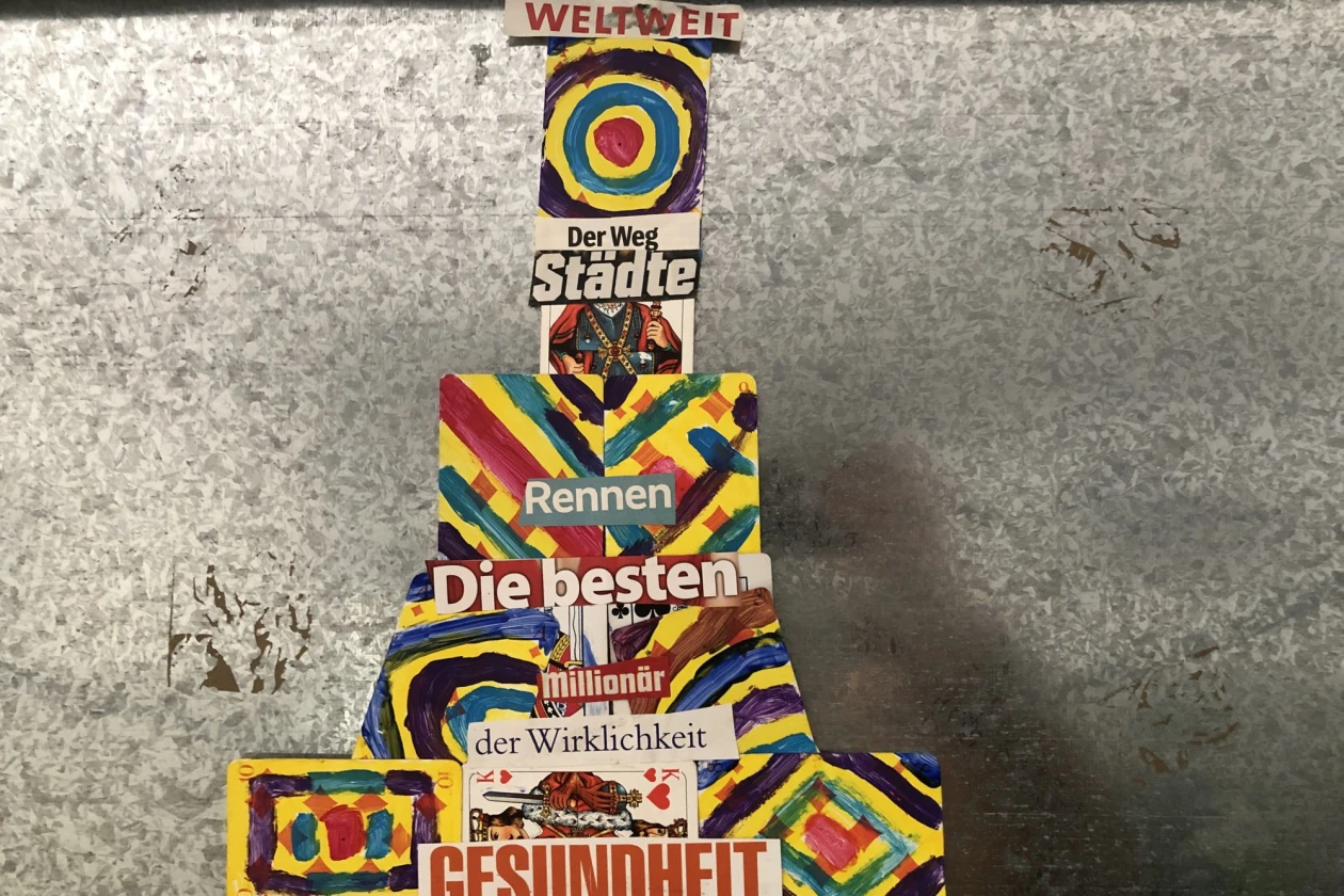 Das Kunstwerk zeigt farbige Bildteile mit Texten als Kollage vor einem grauen Hintergrund.