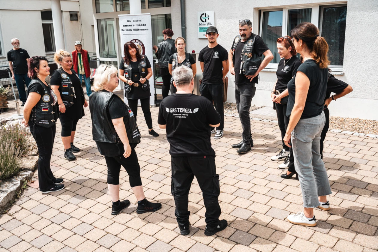 Eine Gruppe von Menschen in schwarzen T-Shirts steht auf einem Platz vor einem Geb&auml;ude und scheint an einem gemeinsamen Event oder einer Veranstaltung teilzunehmen