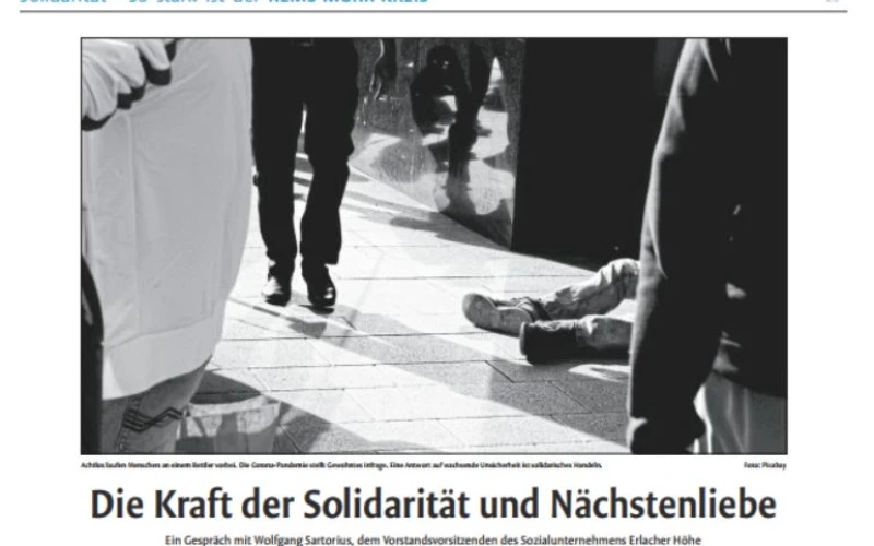 Schwarzwei&szlig;fotografie von Beinen und einer am Boden liegenden Person, die eine soziale Notsituation auf der Stra&szlig;e andeutet, mit &Uuml;berschrift: "Die Kraft der Solidarit&auml;t und N&auml;chstenliebe.