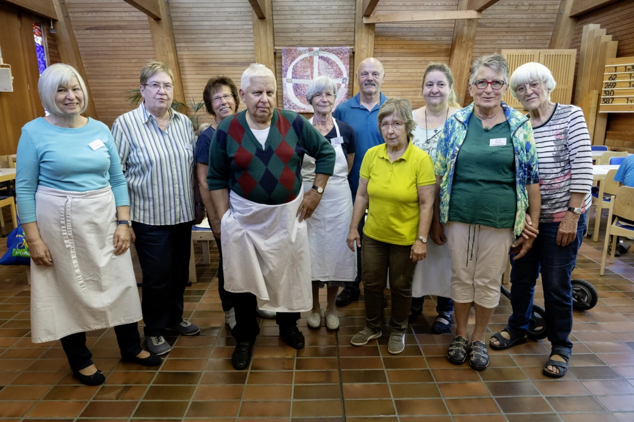 Zehn Personen stehen in einem Raum mit Holzw&auml;nden. Drei von ihnen tragen wei&szlig;e Sch&uuml;rzen. Sie schauen freundlich in die Kamera.