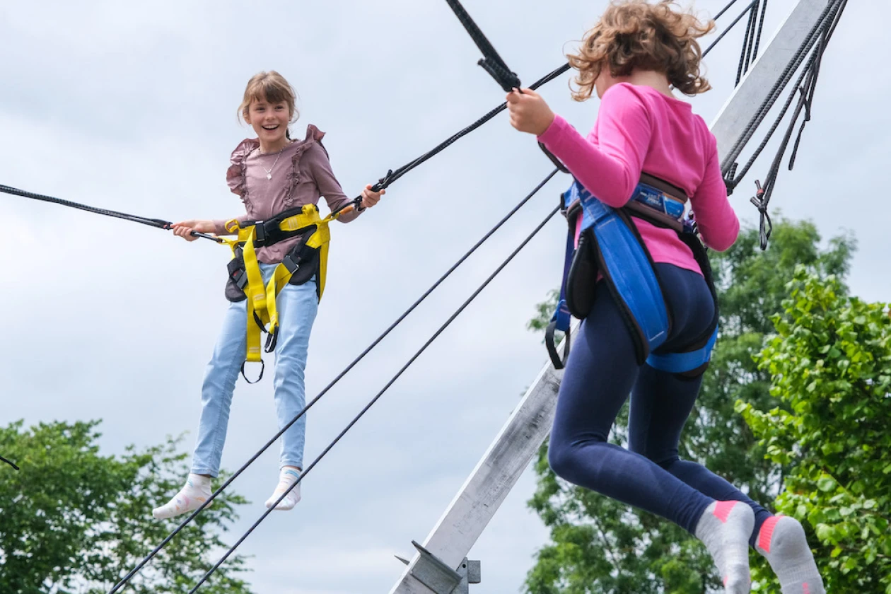 Zwei Kinder springen freudig auf einem Bungee-Trampolin.