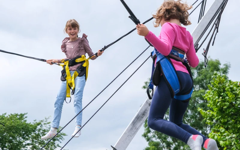 Zwei Kinder springen freudig auf einem Bungee-Trampolin.