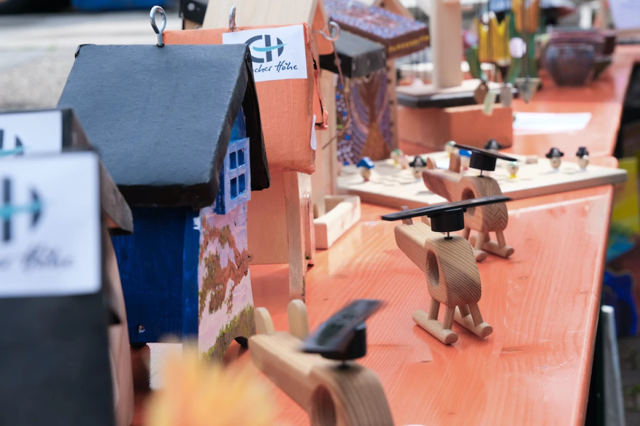 Vogelh&auml;user und Holzspielzeug auf einem orangefarbenen Biertisch, die zum Kauf ausgestellt sind.