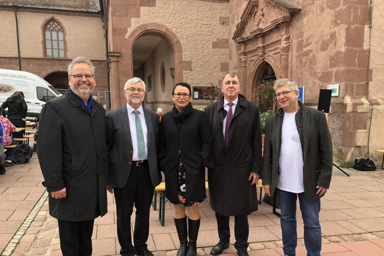 F&uuml;nf Personen stehen vor einem historischen Geb&auml;ude und blicken direkt in Kamera.