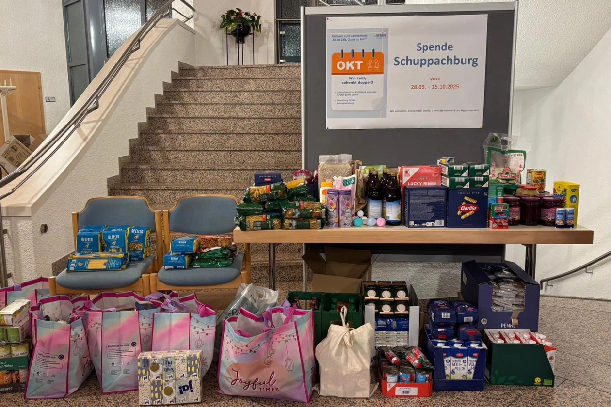 Eine gro&szlig;e Spendenaktion mit zahlreichen Lebensmitteln, Hygieneprodukten und Sachspenden, die auf einem Tisch und auf dem Boden vor einer Treppe organisiert sind