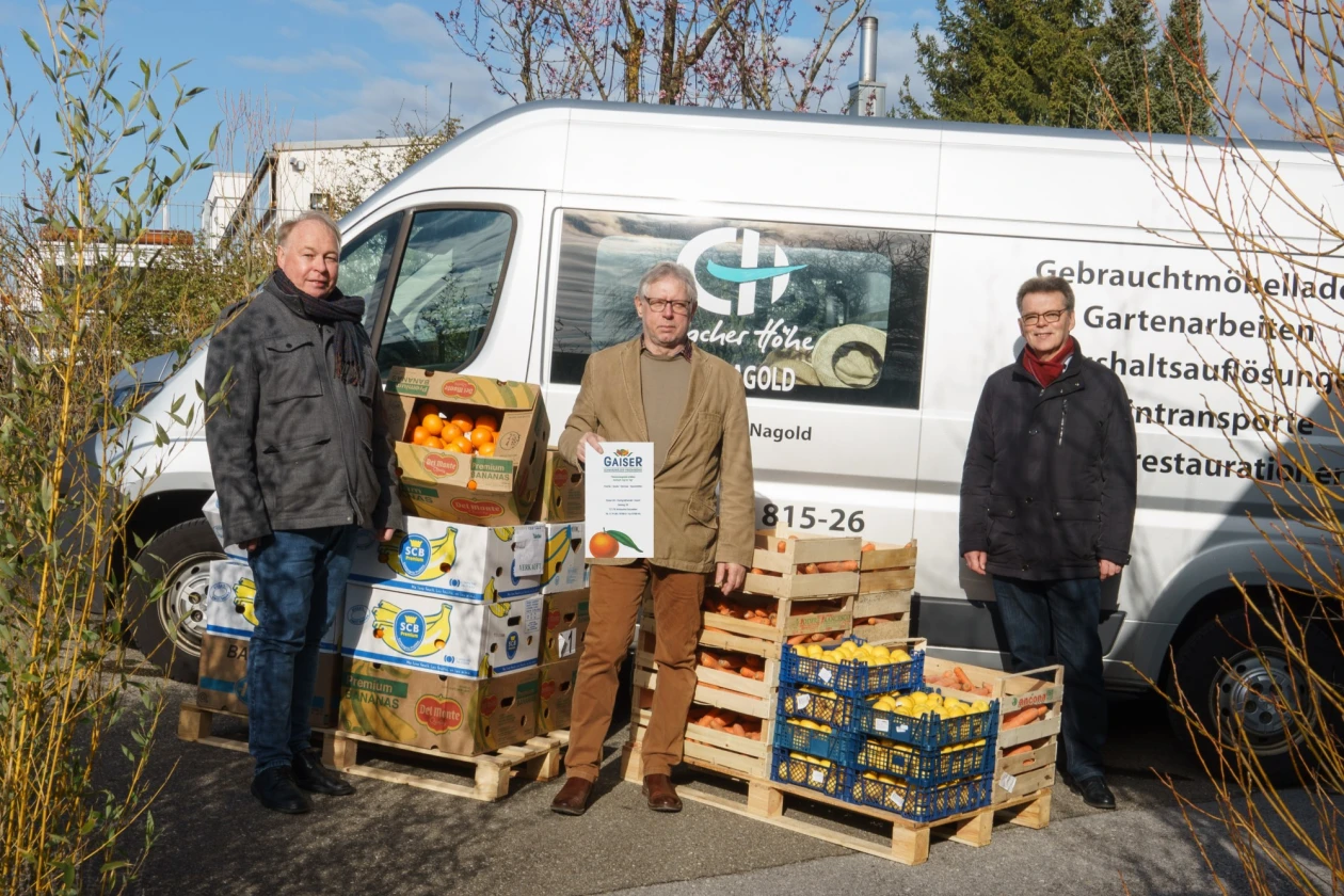 Drei Personen stehen vor einem Transporter mit dem Logo der Erlacher H&ouml;he. Vor ihnen stehen mehrere Kisten mit Orangen und Mandarinen.