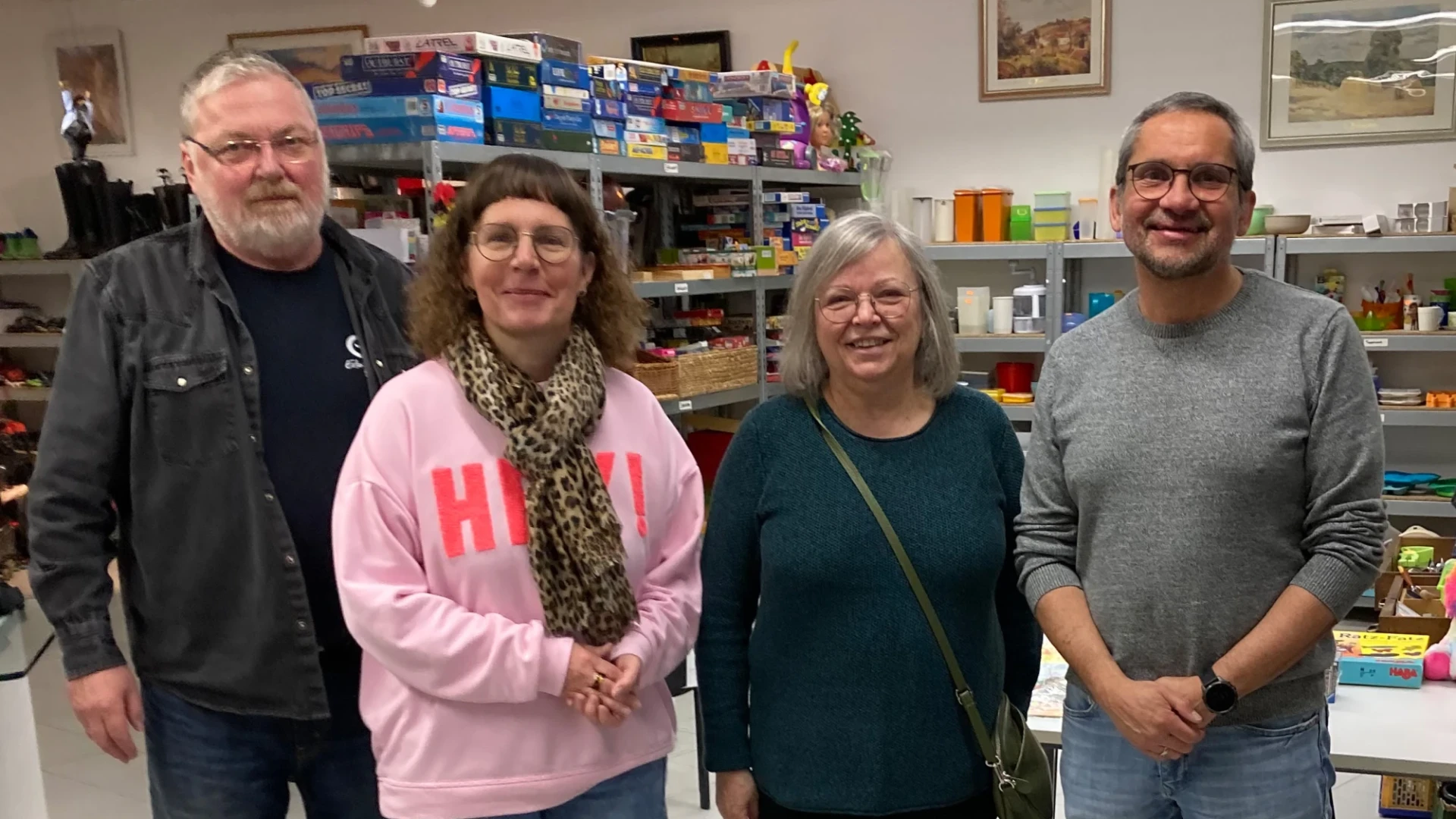 Vier Personen, zwei Frauen und zwei M&auml;nner, stehen in einem Laden vor Regalen mit Gebrauchtwaren.