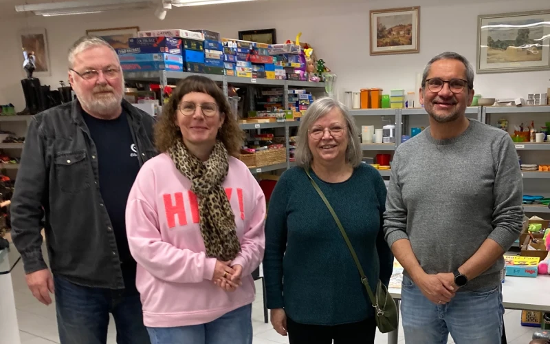 Vier Personen, zwei Frauen und zwei M&auml;nner, stehen in einem Laden vor Regalen mit Gebrauchtwaren.