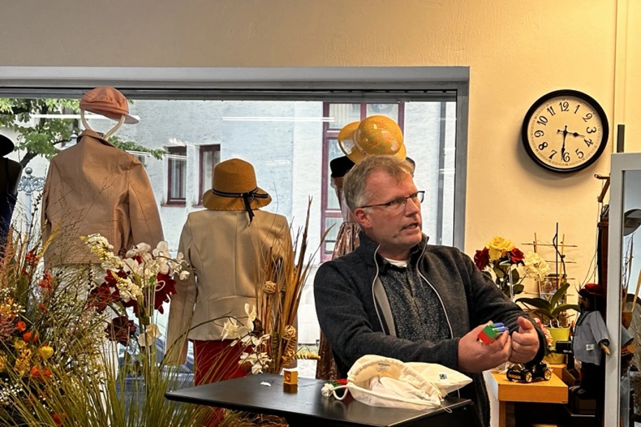 Ein Mann steht in einem Laden vor einem Stehtisch und ist in ein Gespr&auml;ch vertieft.