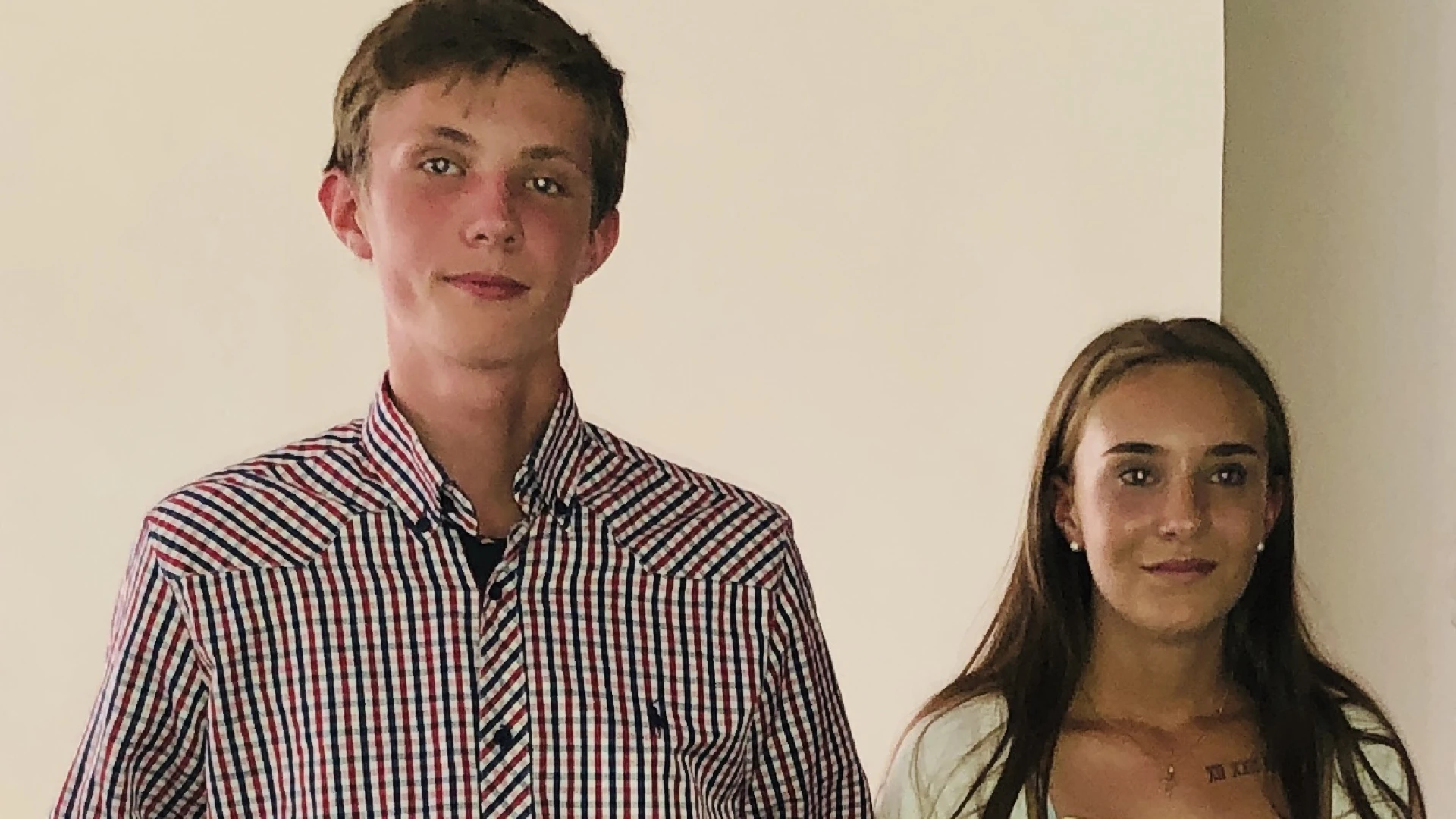 Zu sehen ist links ein Junge in einem karierten Hemd, rechts ein M&auml;dchen in einer wei&szlig;en Jacke. Beide halten ein Dokument in der Hand, das mit dem Logo der Erlacher H&ouml;he versehen ist.