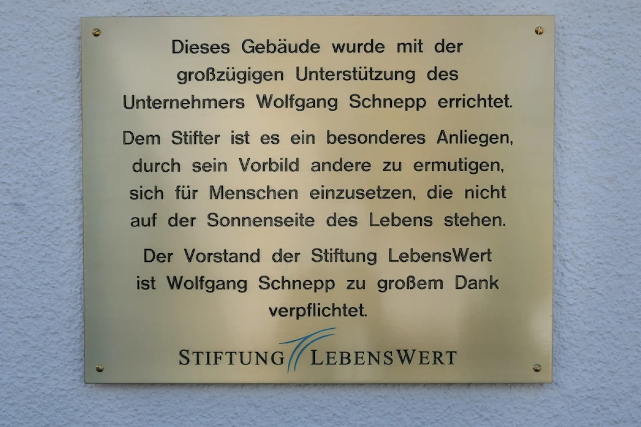 Eine Gedenktafel aus Messing ist an einer Hauswand befestigt.