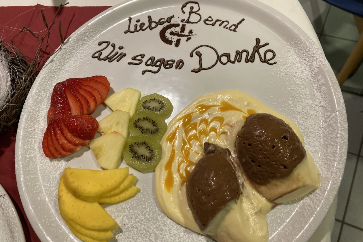 Dessertteller mit Erdbeeren, Ananas, Kiwi, Mousse und Creme und der Aufschrift "Lieber Bernd - Wir sagen Danke".