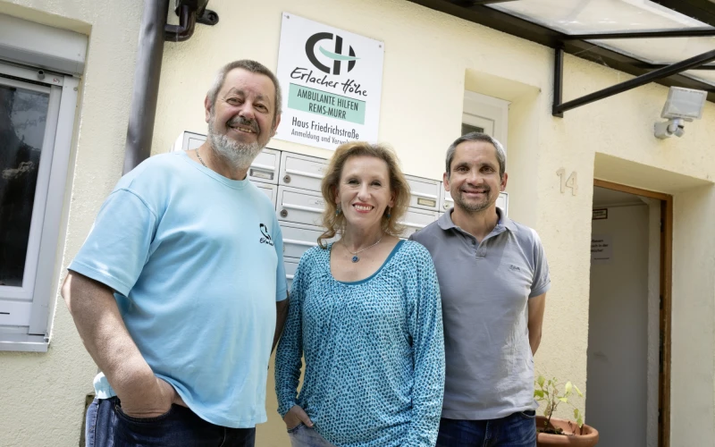 Zwei M&auml;nner und eine Frau stehen vor einem Geb&auml;ude mit der Beschilderung Erlacher H&ouml;he "Ambulante Hilfen Rems-Murr".