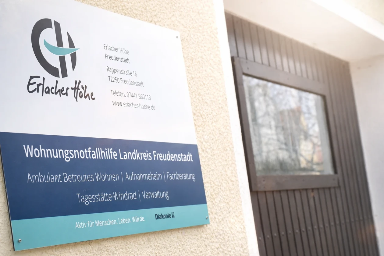 Eingangsschild Wohnungsnotfallhilfe Landkreis Freudenstadt mit allen Infos. Im Hintergrund eine Garagent&uuml;r.