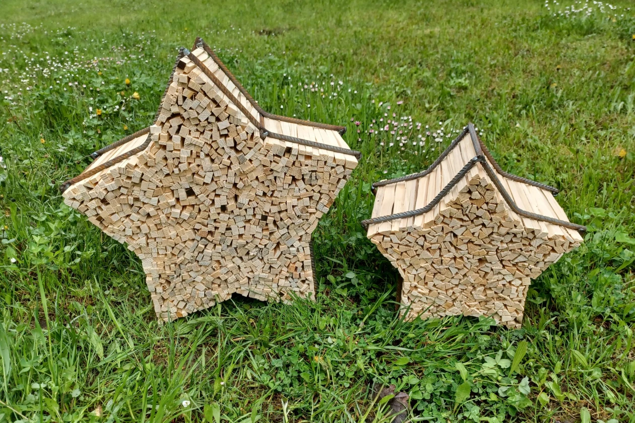 Zwei sternf&ouml;rmige Metallgestelle mit Anz&uuml;ndholz stehen auf einer Wiese.