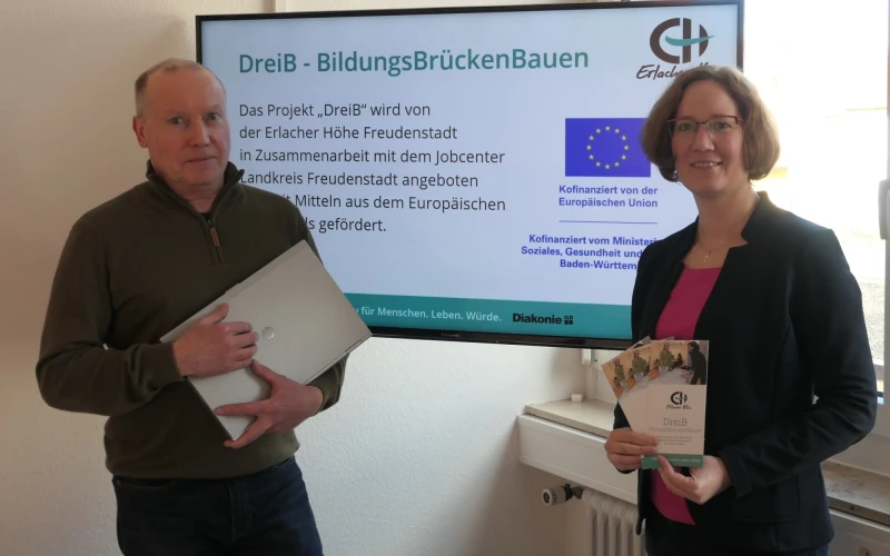 Zwei Personen pr&auml;sentieren das Projekt "DreIB - BildungsBr&uuml;ckenBauen" vor einer Informationstafel