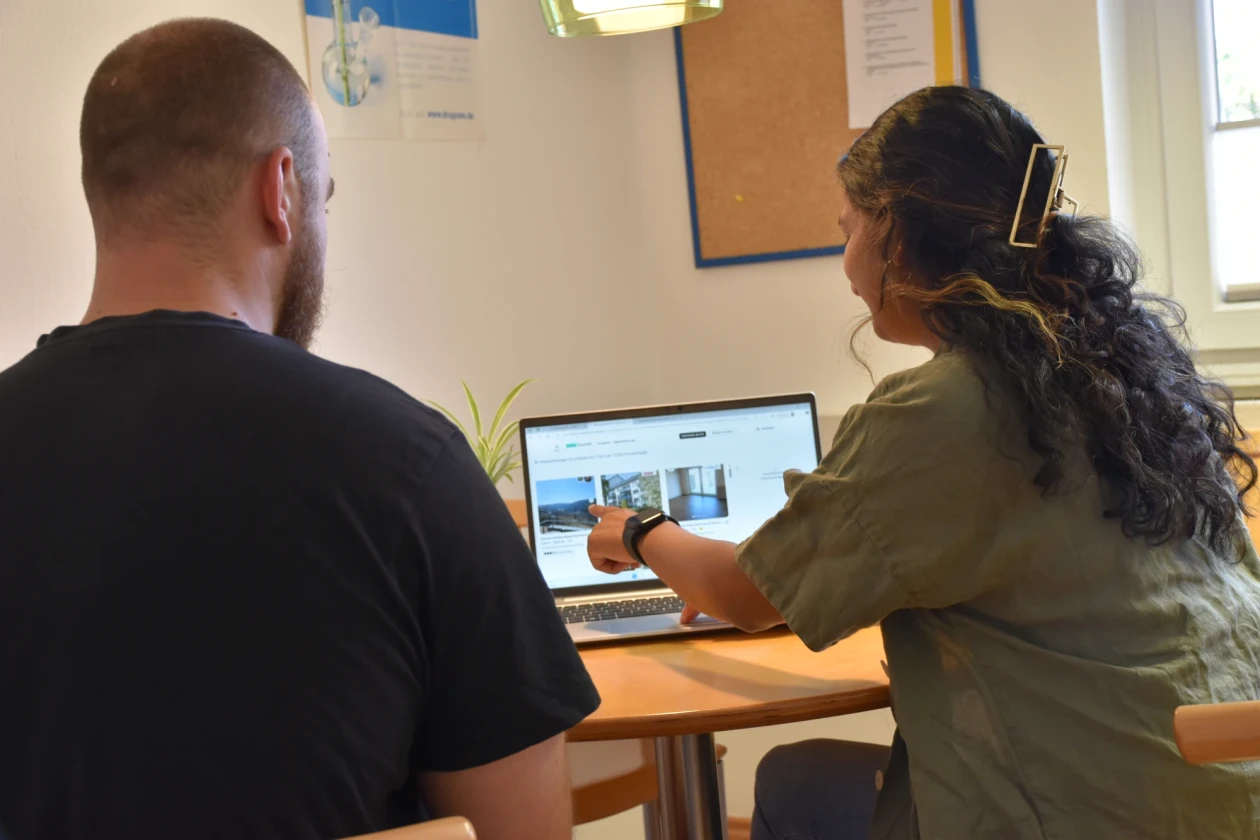 Eine Frau und ein Mann sitzen an einem Tisch und suchen am Laptop nach freien Wohnungen.