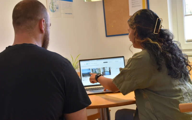 Eine Frau und ein Mann sitzen an einem Tisch und suchen am Laptop nach freien Wohnungen.