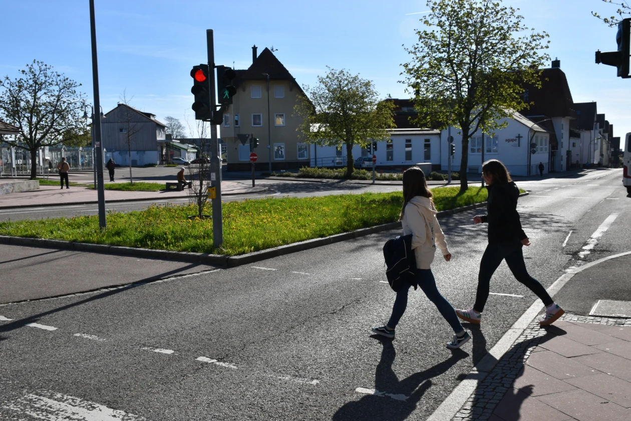 Die Streetworkerinnen gehen zum Stadtbahnhof Freudenstadt &uuml;ber eine gr&uuml;ne Ampel. Im Hintergrund blauer Himmel und H&auml;user.