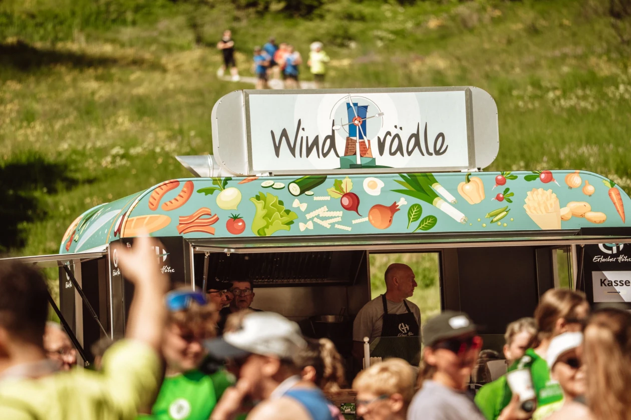 W&auml;hrend einer Veranstaltung steht unser Windr&auml;dle in einer Menschenmenge im Hintergrund gro&szlig;e gr&uuml;ne Wiese und es ist ein warmer Sommertag