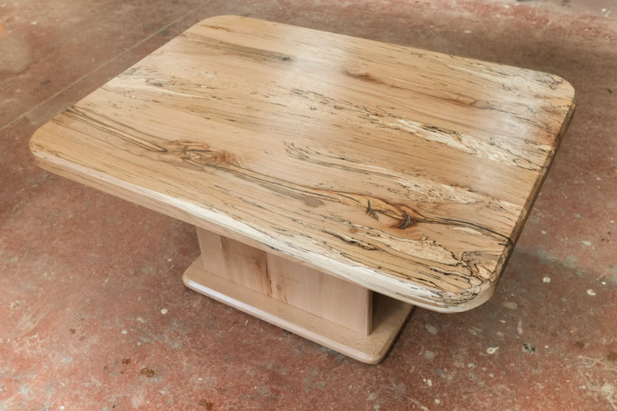 Rustikaler Holztisch mit gemaserter Holzoberfl&auml;che. Die Tischplatte weist nat&uuml;rliche Holzmaserungen und leichte Unregelm&auml;&szlig;igkeiten auf.