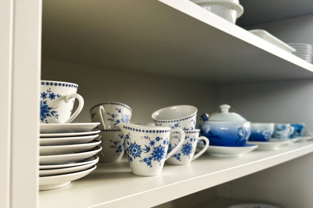 Ein Regal voll mit verschiedenem Geschirr, Tassen, Teller, Teekanne.