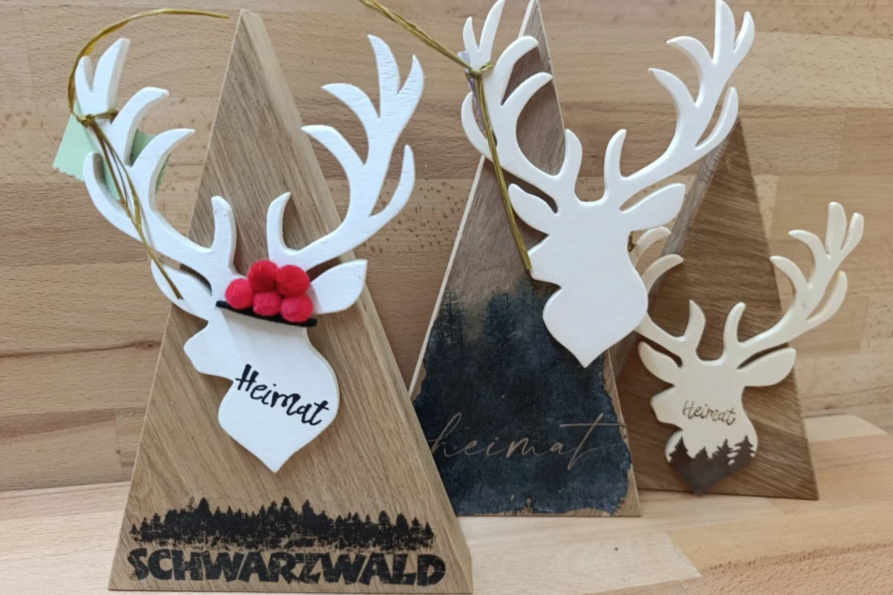 3 sch&ouml;ne Dekofiguren aus Holz mit Schwarzwaldhirschen hintereinander gereiht. Die Hirsche sind wei&szlig;.